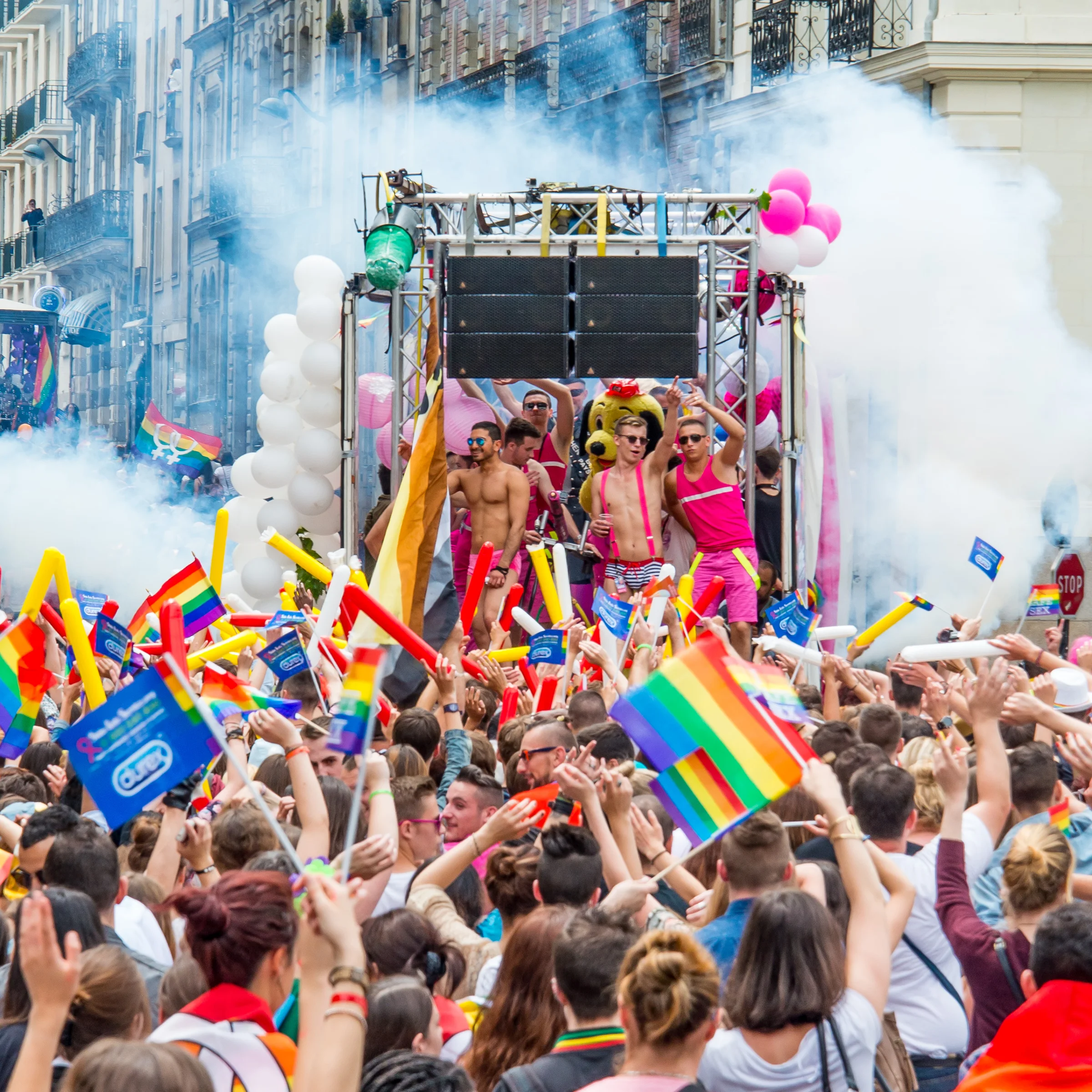 Foule et drapeaux colorés lors d’une marche des fiertés.