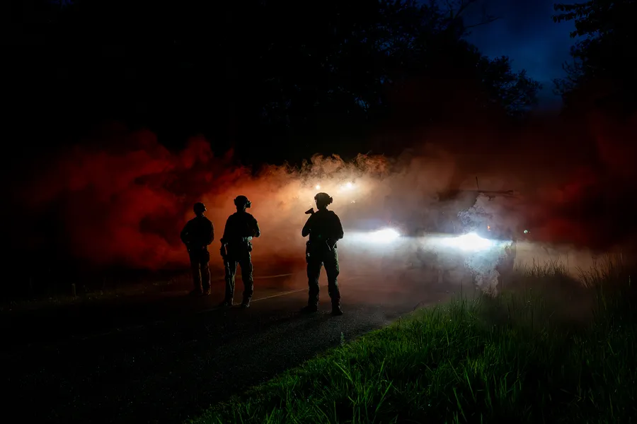 Silhouettes de plusieurs personnes dans une fumée colorée de nuit.