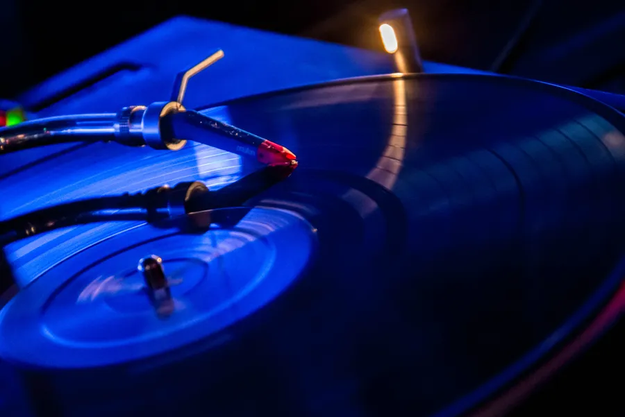 Saphir de platine posé sur un disque vinyle sous une lumière bleue.
