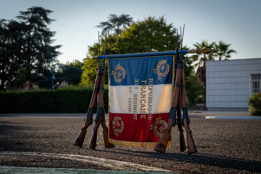 Drapeau cérémoniel présenté entre deux armes longues.
