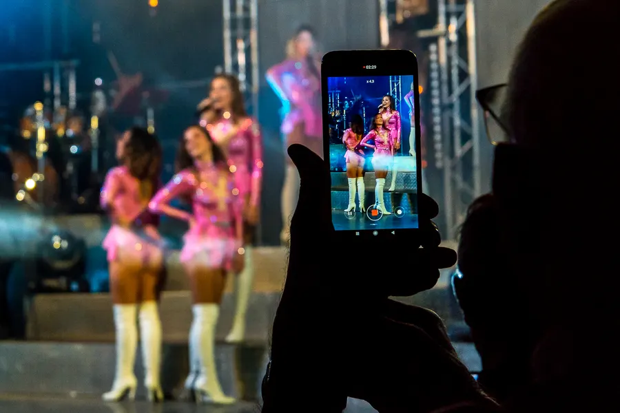 Spectateur filmant une scène de spectacle avec un smartphone.