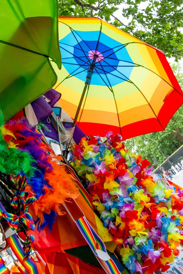 Parapluie arc-en-ciel et accessoires multicolores lors d’un rassemblement.