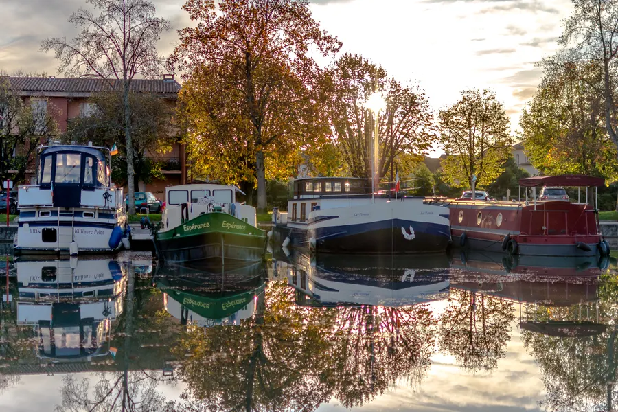 Péniches amarrées se reflétant dans un canal en automne.