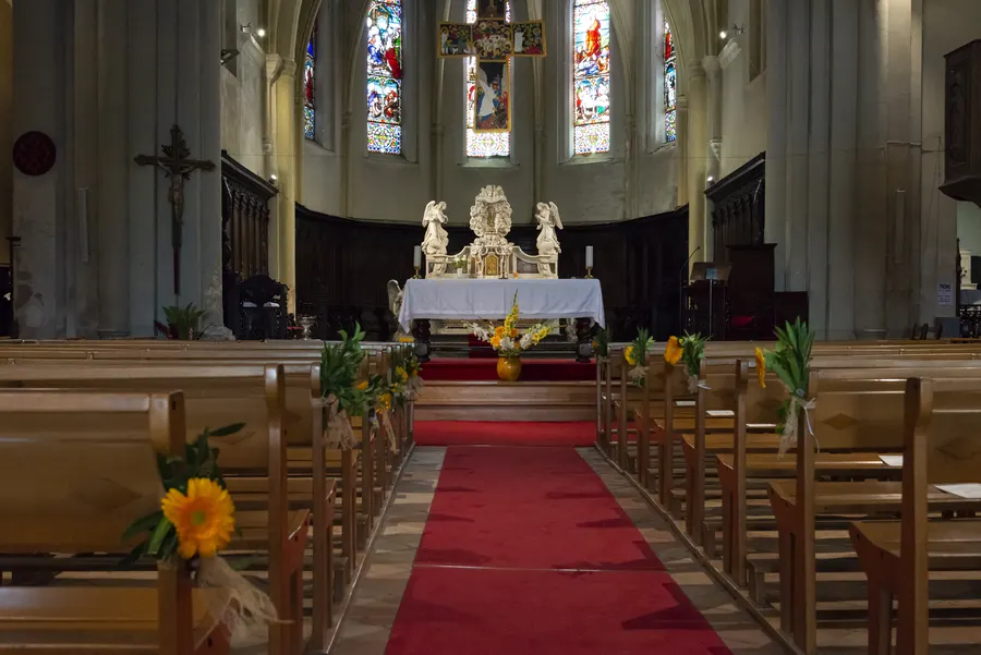 Allée centrale d’une église avec tapis rouge.