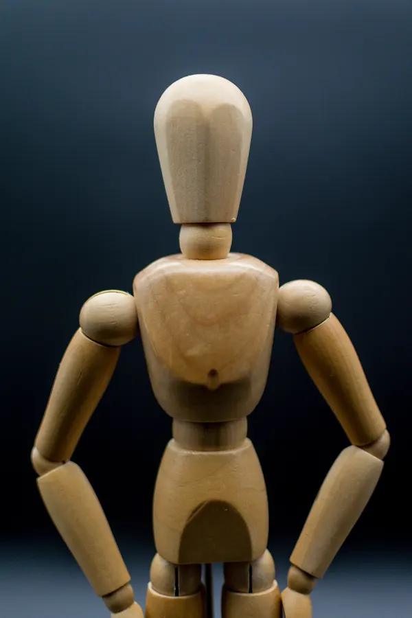 Mannequin articulé en bois photographié de face.