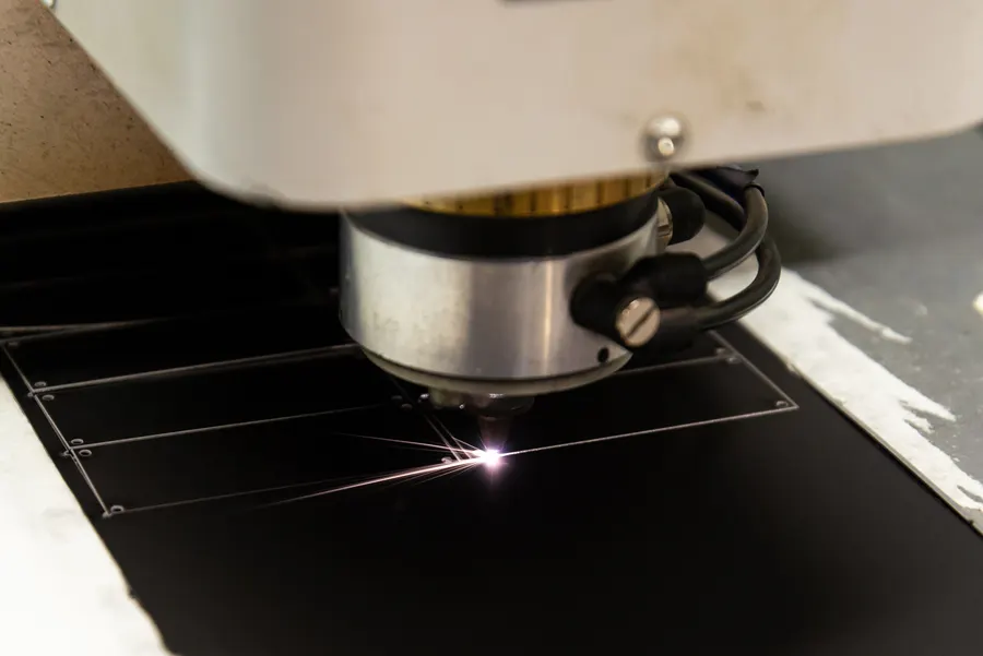 Tête de machine laser travaillant une plaque sombre.