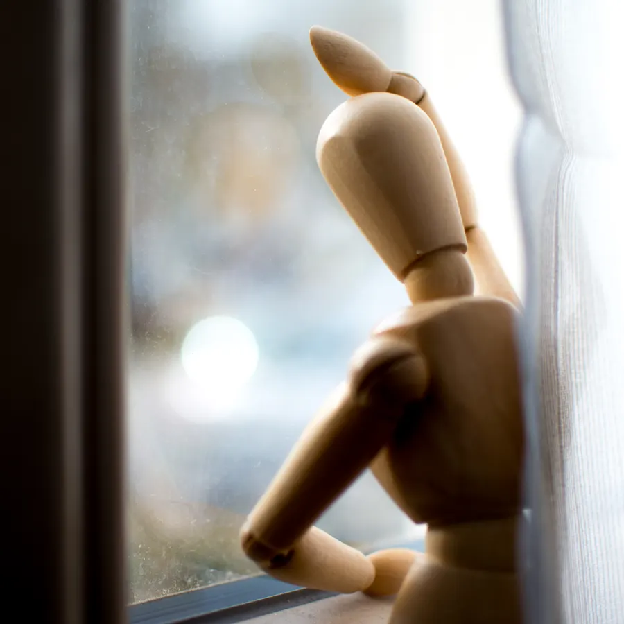 Mannequin articulé en bois regardant par une fenêtre.