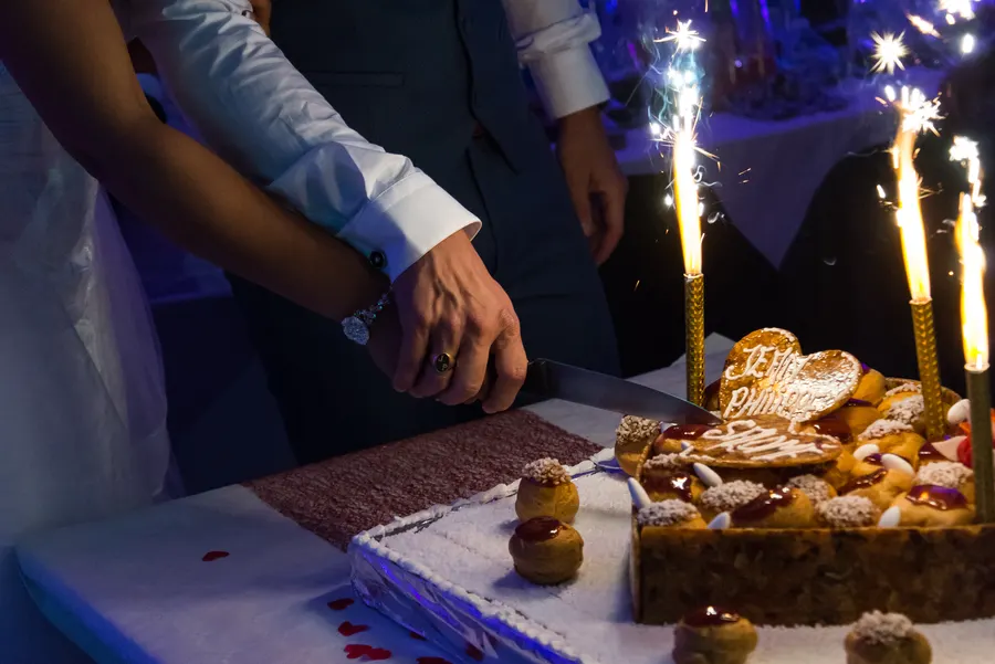Couple coupant un gâteau de mariage entouré d’étincelles.