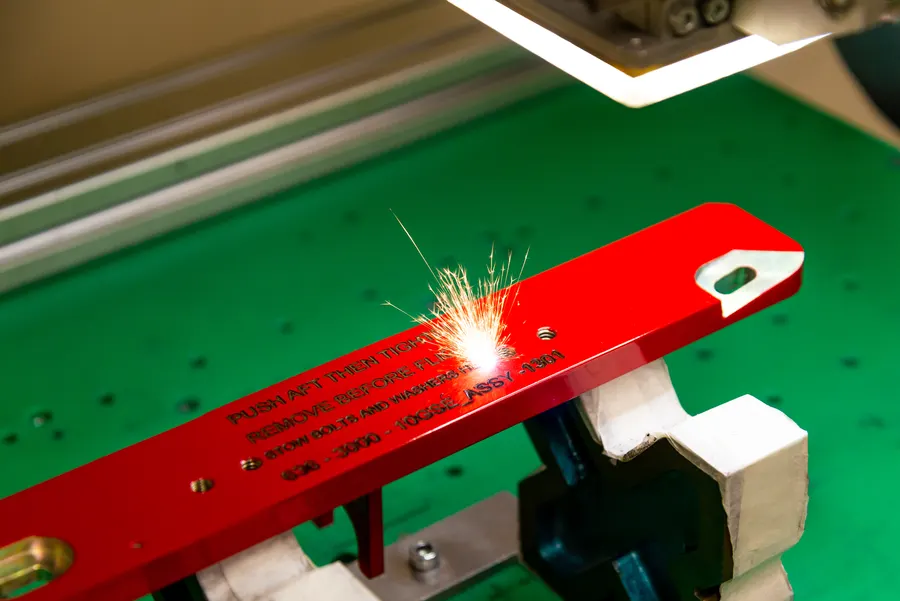 Étincelles produites par un laser sur une pièce métallique rouge.