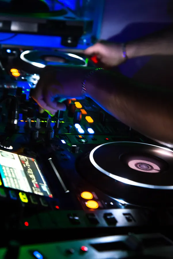 Platine et commandes de DJ sous des éclairages colorés.